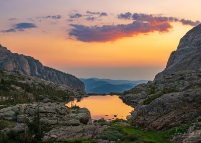 Pink Purple Clouds and Light of Sunrise Reflecting Upon Lake of Glass Below Sky Pond RMNP