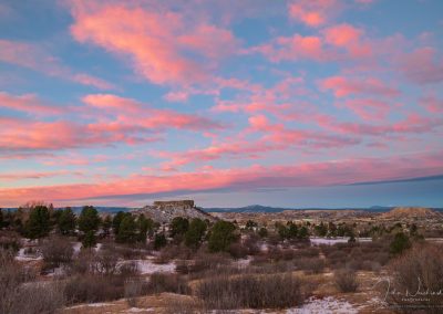 Photo of Pink Clouds over the Illuminated Castle Rock Star Just before Sunrise