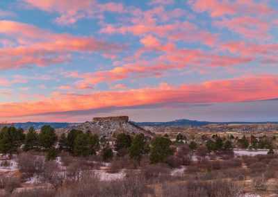 Photo of Colorful Pink Clouds over the Illuminated Castle Rock Star Just before Sunrise
