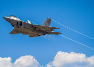 Photo of F-22 Raptor Stealth Fighter with Afterburners and Vapor Trails above the Clouds