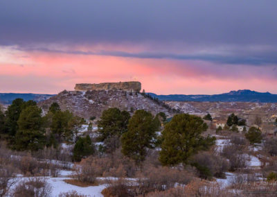 Snow and Dramatic Pink Magenta Clouds behind Illuminated Castle Rock Star