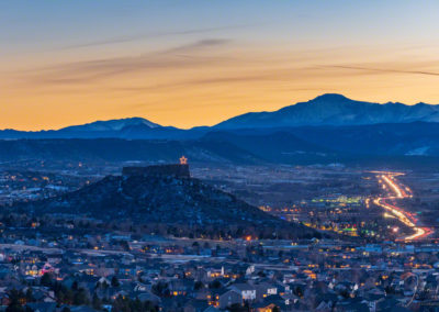 Blue Hour Photo of Illuminated Castle Rock Star and Pikes Peak with Cars on I-25