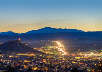 Stunning Panoramic Blue Hour Photo of Illuminated Castle Rock Star and Pikes Peak with Light Trails from Cars on I-25